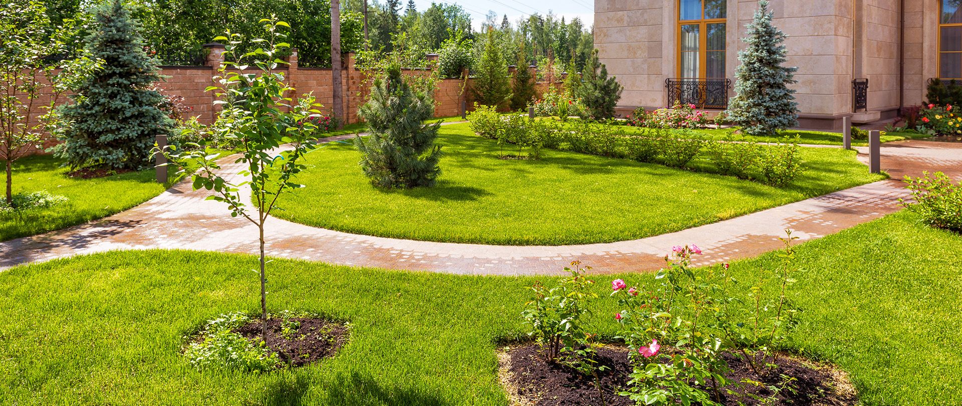 Ein grüner Garten mit einem gepflasterten Weg drumherum | Heinrich Niestroj Haus- und Grundstücksservice